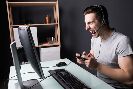 technology, gaming, entertainment, let's play and people concept - angry screaming young man in...