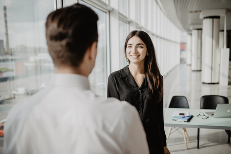 Businessman shaking female hand above the table. Business agreement and partnership concept. Partners closing a deal, view over the shoulder. Formal greeting gesture, effective negotiationsの写真素材