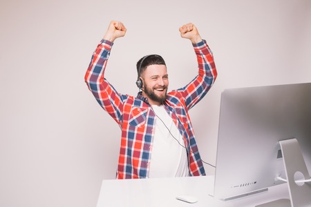 Young handsome man with happy winning emotions of victory or good news in front of pc monitor at...