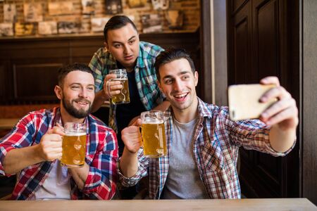 people, leisure, friendship, technology and bachelor party concept - happy male friends taking...