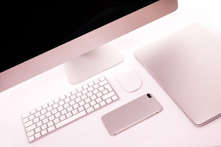 Modern workplace with metallic pc with keyboard and mouse, mobile phone, metalic laptop lying on a desk isolated on white background.の写真素材