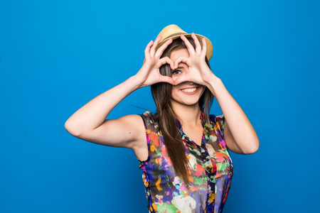 Beautiful young woman in sun hat is showing heart shape hand sign.の写真素材