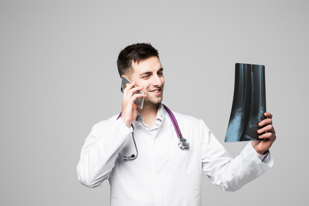 Young handsome doctor with stethoscope working. Discussing the patient's x-ray image on mobile phone.の写真素材