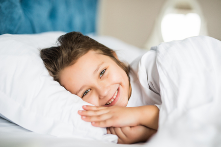 Adorable little girl awaked up in her bedの写真素材