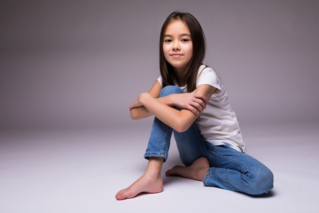 lovely little girl sitting on the floor, isolated on white backgroundの写真素材