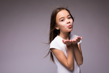 Cute girl is blowing a kiss, isolated over whiteの写真素材