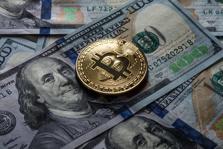 Golden bitcoin coins on a paper dollars money and dark background with sun. Virtual currency. Crypto...