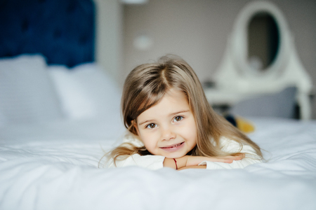 Cute little girl in pajamas on the bed in the morningの写真素材