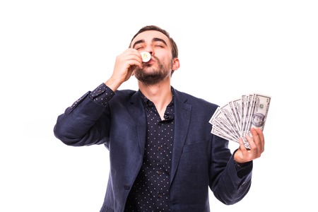 Young handsome man in suit kiss golden bitcoin with dollar cash in other hand isolated on whiteの写真素材