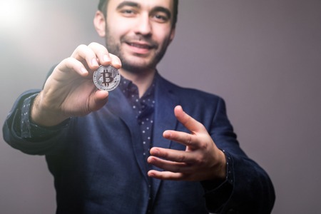 Close up of Handome business man pointed bitcoin on camera isolated on dark background with tonnedの写真素材