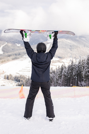 Man standing with snowboard over his headの写真素材