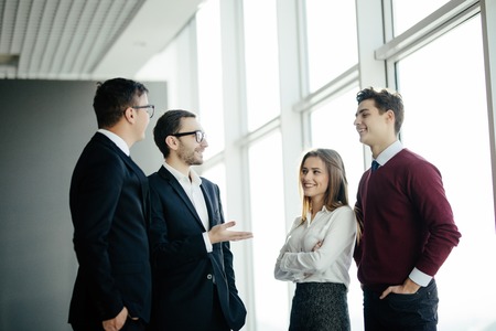 professional business people standing around in informal groups chatting as they wait for a meeting