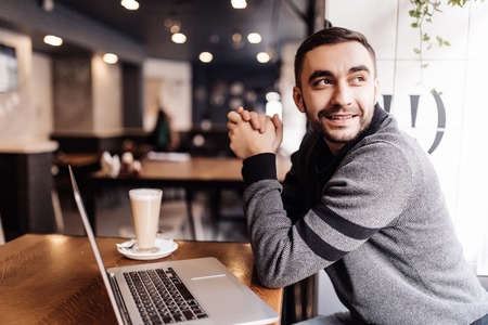 Handsome man drinking coffee while working in a cafeの写真素材