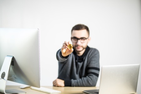 Handsome man at work place with pc and laptop pointed bitcoin moden isolated whiteの写真素材