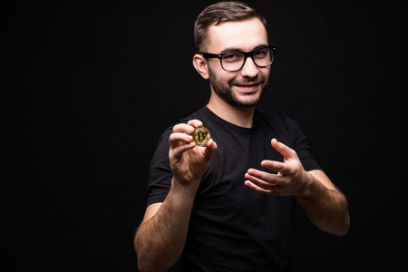 Handsome man in glasses wear in black shirt present bitcoin isolated on black backgroundの写真素材