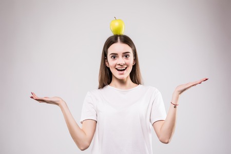 young woman hold green fresh apple on head, female happy smile think looking up side to empty copy space, isolated on white background natural organic food fruit conceptの写真素材