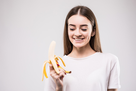 Young woman biting banana isolated on white background.の写真素材