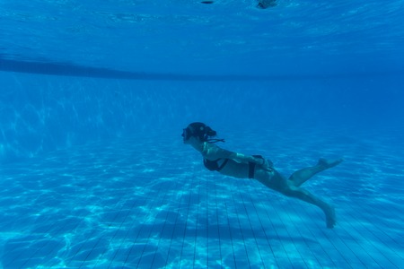 Underwater woman portrait with white bikini in swimming pool.の写真素材