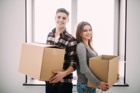 Couple with boxes moving into new home smiling