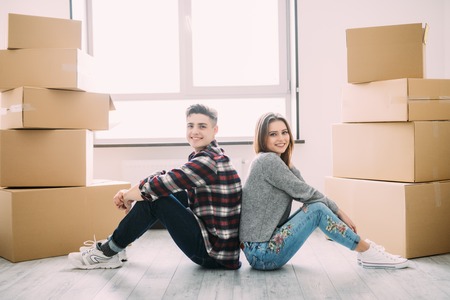 Happy couple sitting on floor around boxes after buying house