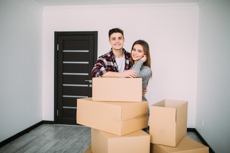 Smiling couple leaning on boxes in new home