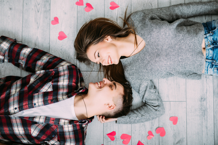 Couple lying on the wooden floor with hearts view from above.の写真素材