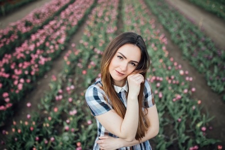 beautiful happy woman in a field of pink tulips smilingの写真素材