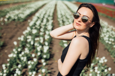Woman in sunglasses in Spring sunny day on tulips Flower field. Mother's Day. Springtimeの写真素材