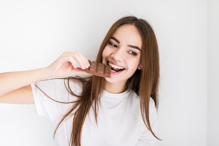 Woman eating chocolate. Beautiful young woman eating chocolate on white