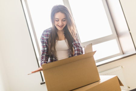Woman packing and unpacking belongings in a carton box when moving home.の写真素材