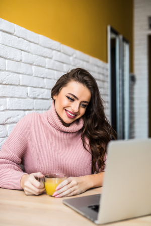 People, accounting, finances, family budget and financial issues concept. Serious young European woman calculating domestic expenses, sitting at dining table in front of open laptop computerの写真素材