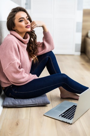 Carefree focused female watches interesting movie on laptop computer with atttentive look sits on floorの写真素材