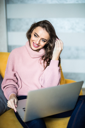 Caucasian woman using laptop computer for sending e-mail, sitting on sofaの写真素材