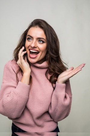 Smiling woman talking on the smart phone isolated on a greyの写真素材
