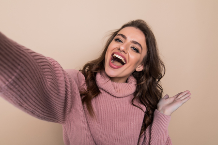 Portrait of a smiling cute woman making selfie photo on smartphone isolatedの写真素材