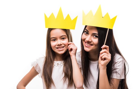 Mother and daughter posing with paper crowns on stick isolated on whiteの写真素材