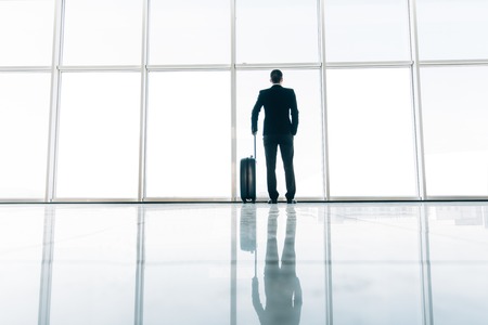 Rear of Businessman and suitcase in the airport waiting for flight. Travel concept, traveler suitcases in airport terminal.の写真素材