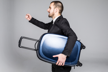 Young business man with suitcase on grey background.の写真素材
