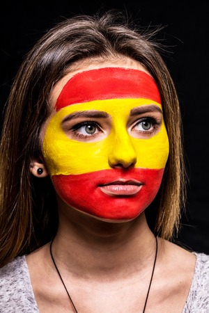 Portrait of woman face supporter fan of Spain national team with painted flag face isolated on black background.の写真素材