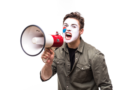 Handsome man supporter loyal fan of Korea Republic national team with painted flag face screaming into megaphone with pointed hand.の写真素材