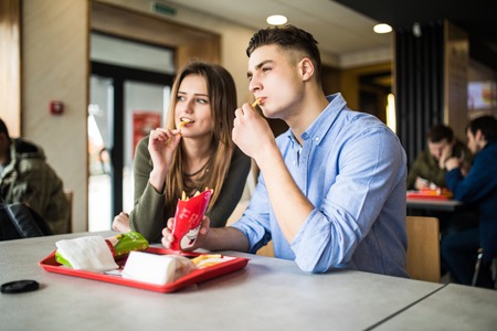 Handsome smiling couple enjoying in fries, having fun together. Consumerism, food, lifestyle conceptの写真素材