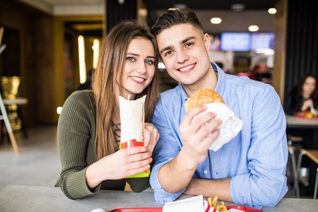 Happy loving couple enjoying and eating fast foodの写真素材