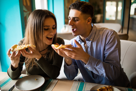Couple sharing pizza and eating together happilyの写真素材