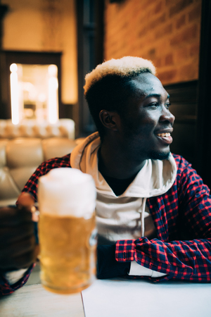 Happy handsome african american young man drinking beerの写真素材