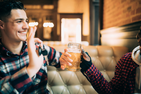 Young guy is holding car keys and refusing to drink beer from his friend in pubの写真素材