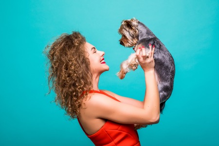 Beautiful woman's Yorkshire terrier dog gives kissesの写真素材