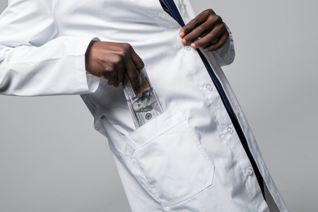 A doctor putting money in his pocket isolated on white backgroundの写真素材