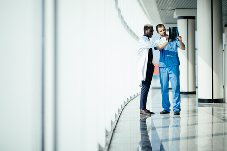 two male doctors reviewing x-ray in hospital corridorの写真素材