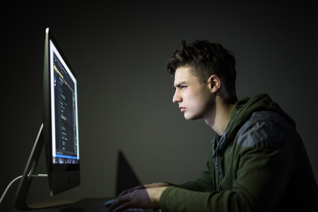 Young man hacking server in dark room