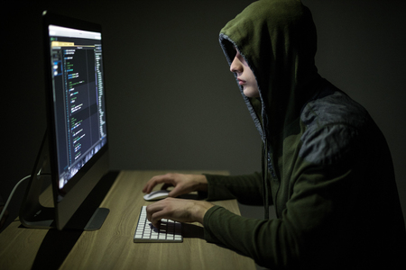 Man wearing hoodie hacking server in dark room